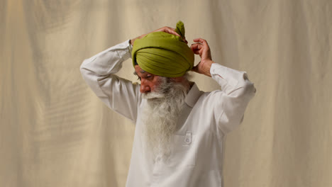 Studio-Shot-Of-Senior-Sikh-Man-With-Beard-Tying-Fabric-For-Turban-Against-Plain-Background-3